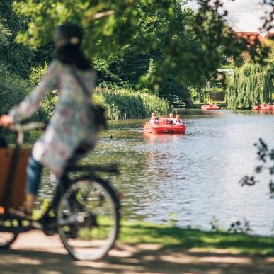 Kvinde på christianiacykel med vandcykler på aaen i baggrunden