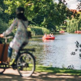 Kvinde på christianiacykel med vandcykler på aaen i baggrunden